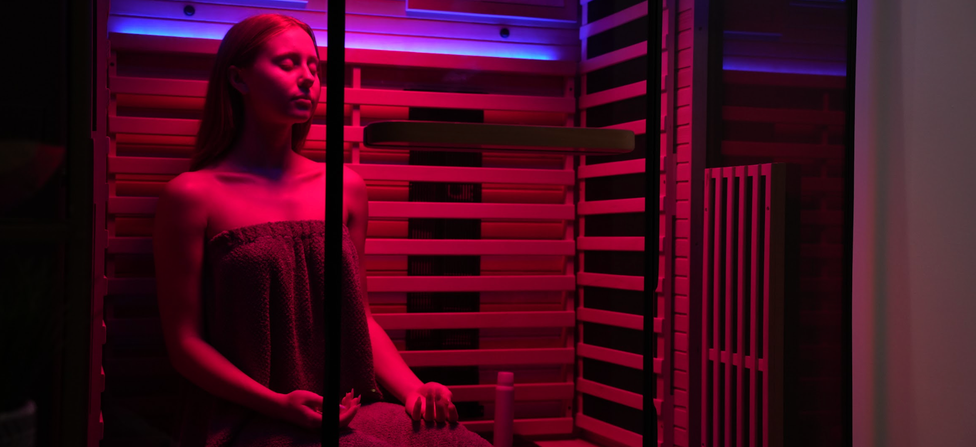 Person sitting inside a infrared sauna with red lighting
